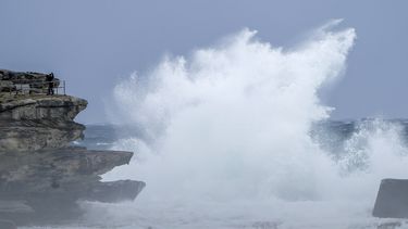 Gente al borde de un acantilado mientras las olas golpean la costa en Bondi Beach, Sydney, Australia, el domingo 3 de julio de 2022. Miles de vecinos en los suburbios de Sydney recibieron orden de evacuar el domingo después de que fuertes lluvias provocaran crecidas y desbordamientos, que las autoridades describieron como emergencias que ponían vidas en peligro.&nbsp;