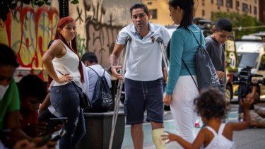 El migrante Eduardo García de pie con muletas, y rodeado de su familia afuera de la sede de Caridades Católicas, en Nueva York.&nbsp;