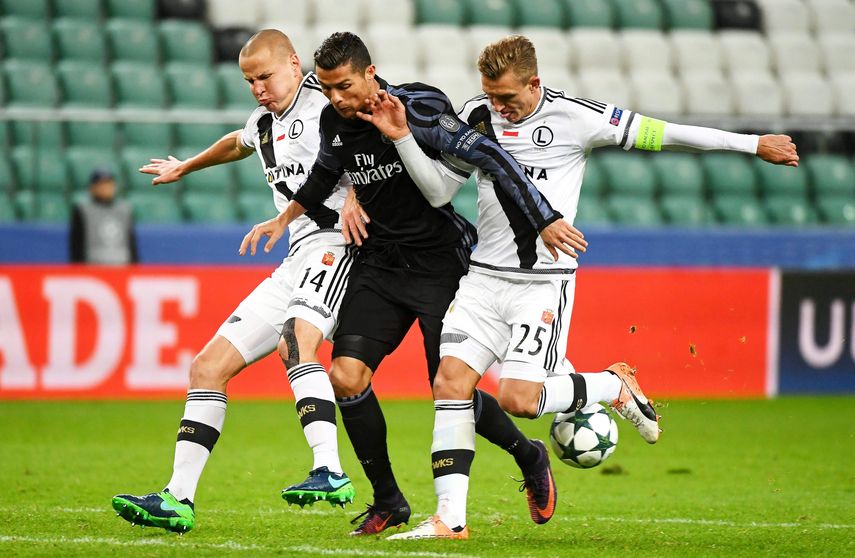 Cristiano Ronaldo (centro) del Real Madrid disputa el balón con Jakub Rzezniczak (derecha) y Adam Hlousek (izquierda) del Legia de Varsovia