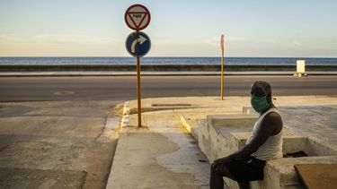 Un hombre que usa una máscara como precaución contra la propagación del nuevo coronavirus descansa en el malecón del malecón en La Habana, Cuba, el lunes 31 de agosto de 2020.