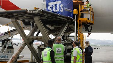 Un contenedor con vacunas contra el COVID-19 fabricadas por Oxford/AstraZeneca es bajado del avión a su llegada procedente de India en el aeropuerto internacional en Sao Paulo, Brasil, el viernes 22 de enero de 2021