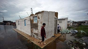 Un joven camina afuera de una casa dañada y rodeado de agua de lluvia tras el paso del huracán Rafel en Batabano, provincia de Mayabeque, Cuba, el 7 de noviembre de 2024.