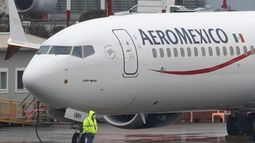 Un trabajador caminando frente a un Boeing 737 Max 9 con el logotipo de Aeroméxico.