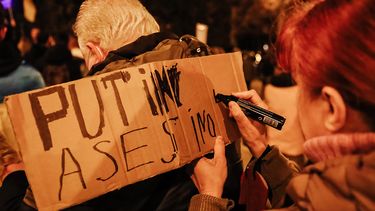 Una mujer escribe un letrero, durante una protesta en Madrid contra la invasión rusa de Vladimir Putin a Ucrania, 2022.