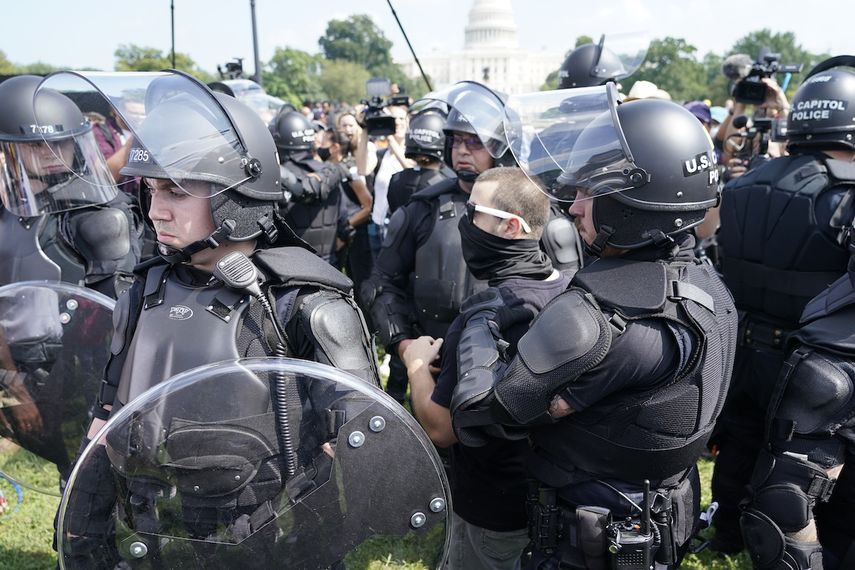 Varios policías rodean a un hombre (al centro, con anteojos) durante un mitin cerca del Capitolio de Estados Unidos el sábado 18 de septiembre de 2021, en Washington, D.C.