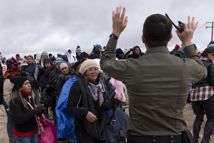 La peruana Julia Paredes, a la izquierda con un gorro blanco, escucha las instrucciones de un agente de la patrulla fronteriza junto a otros solicitantes de asilo, mientras esperan a ser procesados tras cruzar la cercana frontera con México, el jueves 25 de abril de 2024, en Boulevard, California.&nbsp;