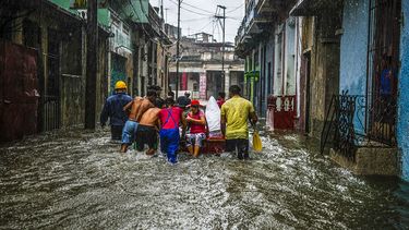 Un grupo de personas avanza por una calle inundada de lluvia en La Habana.