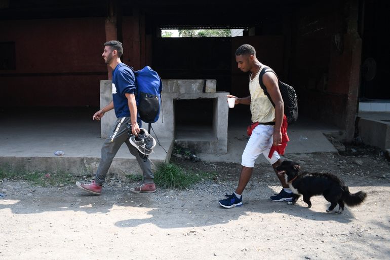 El migrante venezolano Gilberto Rodríguez (derecha) camina con su perro llamado Negro y su compañero migrante Darwin Montiel en una calle de Tecun Uman, Guatemala, en la frontera con Ciudad Hidalgo, México.