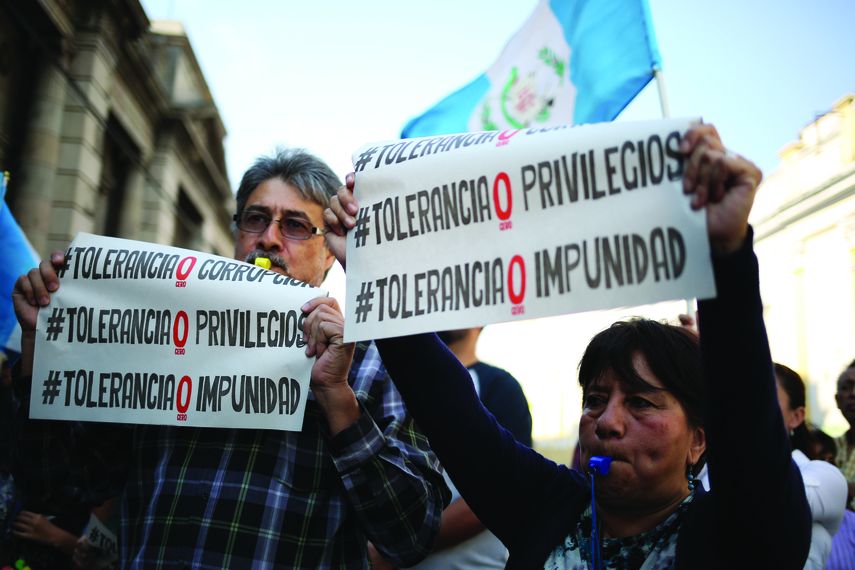 Una pareja sostiene carteles en una protesta para exigirle al Gobierno del presidente guatemalteco Jimmy Morales que aplique la transparencia en sus gestiones en Ciudad de Guatemala.