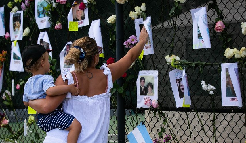 Victoria Mayer y su hijo Antonio visitan un memorial improvisado en el sitio de un edificio derrumbado en Surfside, Florida, al norte de Miami Beach, el 26 de junio de 2021. Victoria dijo que ha vivido en Surfside durante dos años y es originaria de Argentina. Un ingeniero advirtió sobre daños estructurales importantes en un edificio de apartamentos de Florida tres años antes de que colapsara parcialmente, según un informe el 26 de junio, mientras los rescatistas se apresuraban a encontrar a 159 personas aún desaparecidas en la montaña de restos. Se ha confirmado la muerte de cuatro personas después de que el edificio de 12 pisos frente al mar en Surfside colapsara cuando los residentes dormían adentro en las primeras horas del 24 de junio.