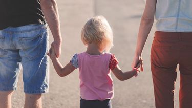 Pareja caminando con su hija por el parque.