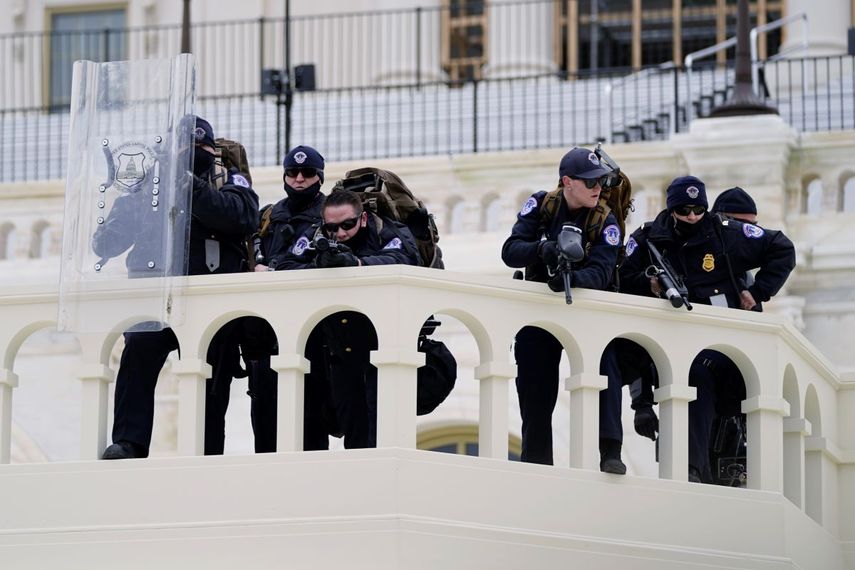Agentes de la policía observan a unos manifestantes que tratan de pasar a través de una barrera de la policía, el miércoles 6 de enero de 2021, en el Capitolio, en Washington.