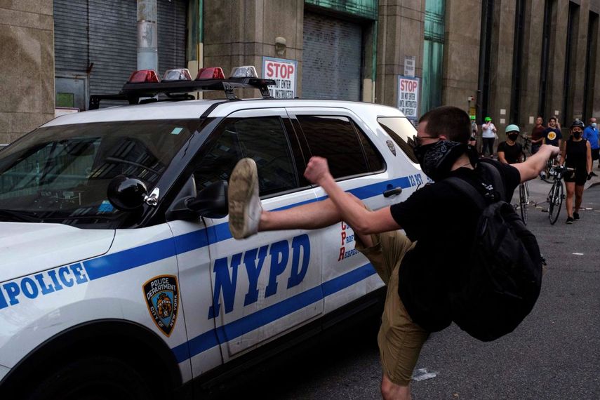 Un joven trata de dañar un vehículo policial en medio de una protesta en Nueva York el 25 de julio del 2020. 