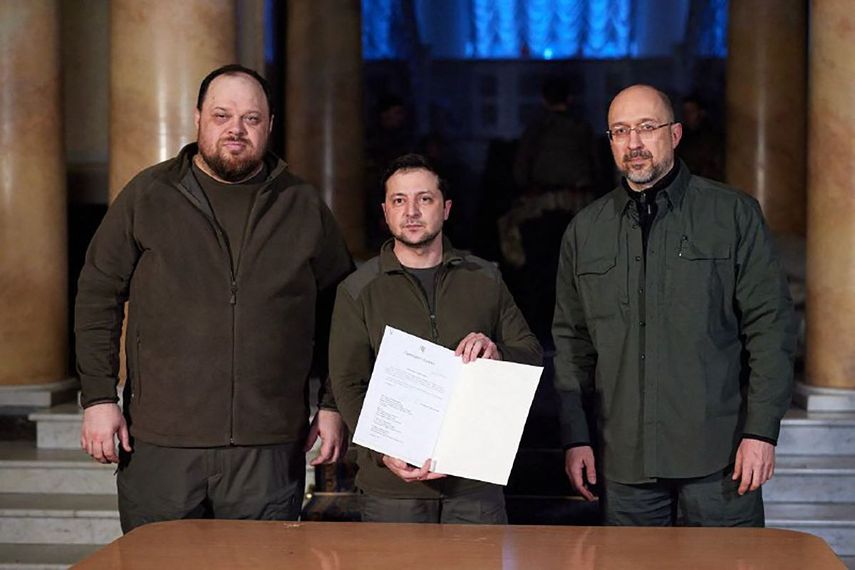 El presidente de Ucrania, Volodymyr Zelensky (centro), al primer ministro de Ucrania, Denys Shmyhal (derecha), y el presidente del Parlamento de Ucrania, Ruslan Stefanchuk, asisten a la firma de la solicitud para integrar a Ucrania la Unión Europea.