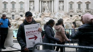 Un hombre sostiene un cartel con la inscripción Entrada frente a la Fontana de Trevi, en el centro de Roma, el 19 de diciembre de 2025.