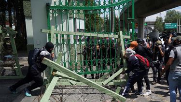 Manifestantes que protestan por la desaparición de 43 estudiantes universitarios retiran las puertas y barreras de una base militar en la Ciudad de México, el viernes 23 de septiembre de 2022