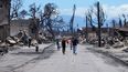 Personas caminan en medio de una calle observando los daños causados por un incendio forestal, el viernes 11 de agosto de 2023, en Lahaina, Hawai.&nbsp;