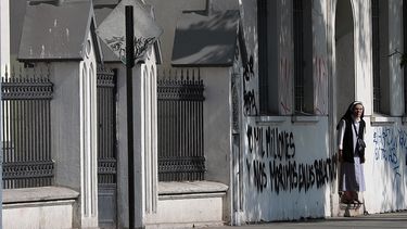 Una monja sale de Iglesia Cristo Pobre cuyas paredes fueron rayadas con mensajes en contra de la visita papal.