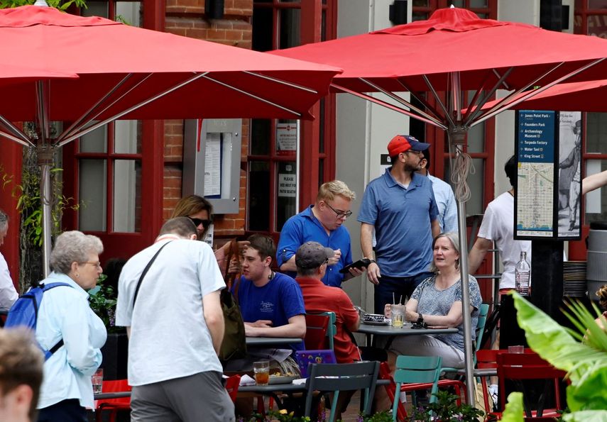 Un empleado atiende a clientes en una terraza de un restaurante.