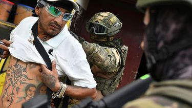 Un militar revisa la espalda de un hombre, comprobando sus tatuajes, en un control en Portoviejo, Ecuador.
