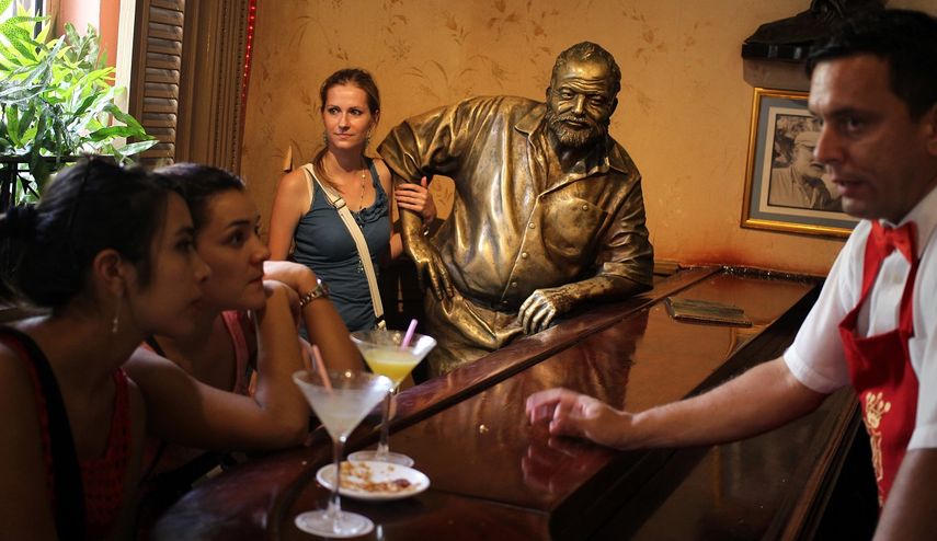 Una joven posa junto a la estatua de Ernest&nbsp;Hemingway&nbsp;en el restaurante Floridita, en La Habana, Cuba, uno de los sitios preferidos por el fallecido escritor norteamericano.