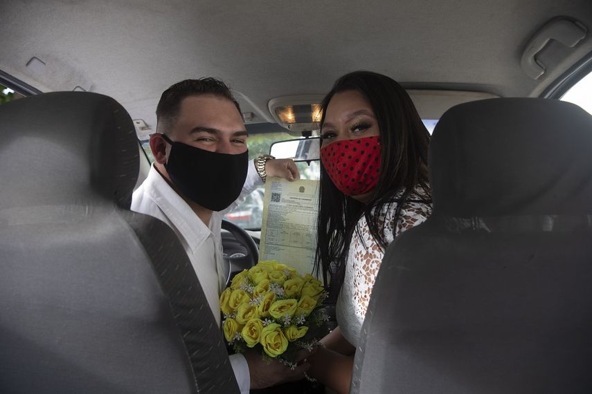 Ayrton (izquierda) y Natasha, con mascarillas para protegerse del coronavirus, posan para un fotograf&iacute;a tras casarse en un drive-thru en un registro del vecindario de Santa Cruz, en R&iacute;o de Janeiro, Brasil, el 28 de mayo de 2020.&nbsp;