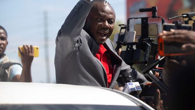 El exsenador haitiano Moise Jean-Charles habla con los medios de comunicación desde un vehículo en el Aeropuerto Internacional Toussaint Louverture, en Puerto Príncipe, Haití, el martes 25 de enero de 2022