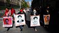 Mujeres con fotografías de sus familiares desaparecidos, que se encuentran entre los 43 estudiantes desaparecidos en Ayotzinapa, México,&nbsp;caminan hacia la puerta del Palacio Nacional donde se reunirán con el presidente Andrés Manuel López Obrador.