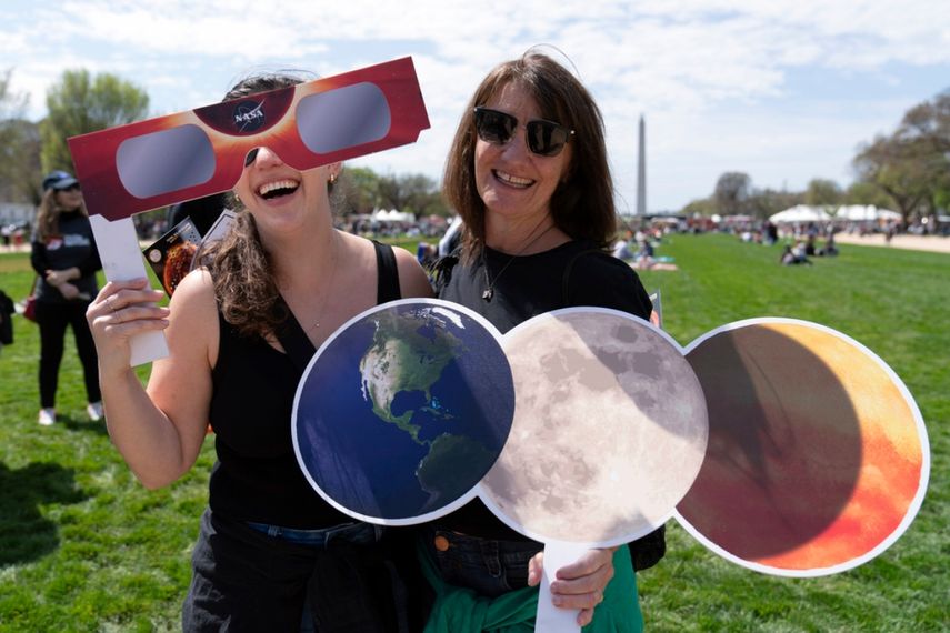 Mackenzie Trumbull, izquierda, y Kathy Trumbull posan para una fotografía mientras se reúnen para observar cómo la luna cubre parcialmente el sol durante un eclipse solar total, visto desde el National Mall en Washington, el lunes 8 de abril de 2024.