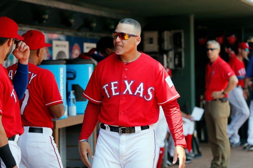 El coach de primera base de los Rangers de Texas, Héctor Ortiz (4), camina en el dugout conversando con los jugadores durante un juego de béisbol ante los Angelinos de Los Ángeles, el domingo 3 de septiembre de 2017, en Arlington, Texas.