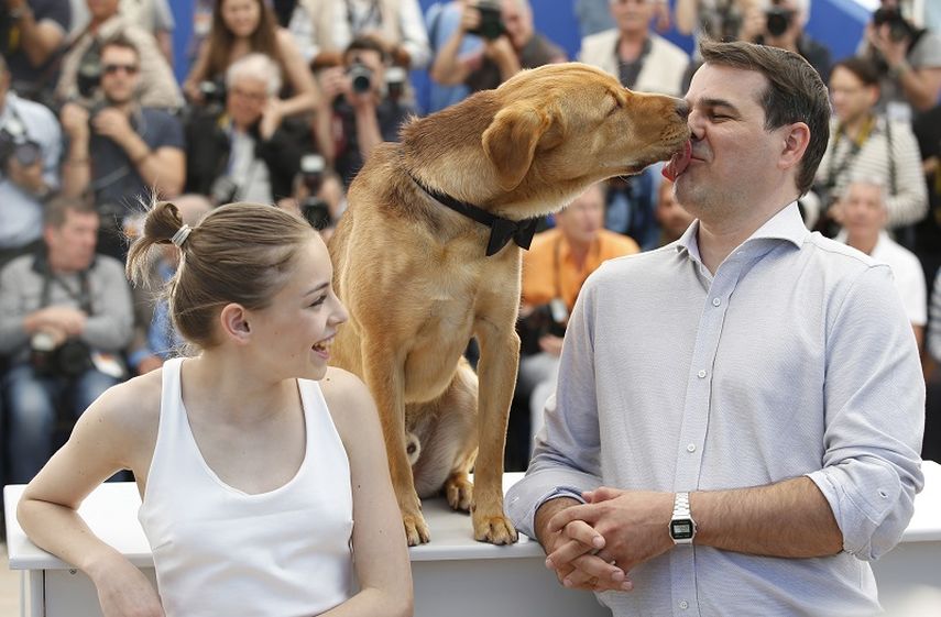 La actriz Zsofia Psotta, izquierda, mira al director Kornél Mndruczó mientras lo besa un perro durante una sesion de fotos para la película White Dog. (AP)