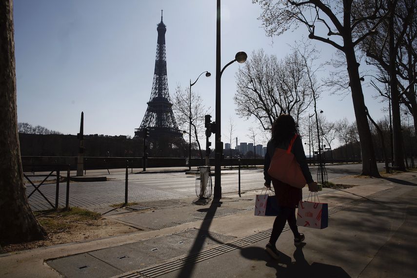Una mujer camina en una calle vacía cerca de la Torre Eiffel durante un confinamiento a nivel nacional para frenar la propagación del nuevo coronavirus, en París, el jueves 26 de marzo de 2020. 