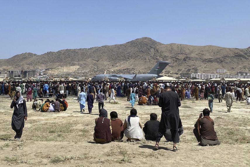 Cientos de personas esperan junto a un avión de transporte C-17 de la Fuerza Aérea de Estados Unidos en el perímetro del aeropuerto internacional de Kabul, Afganistán, el 16 de agosto de 2021.&nbsp;