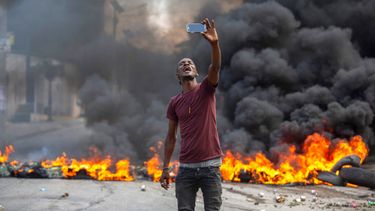 Un manifestante se toma una selfie en una barricada en llamas, el lunes 18 de octubre de 2021, en Puerto Príncipe, Haití.