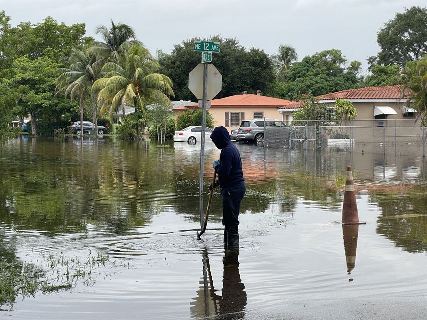 Residente de North Miami intenta limpiar la alcantarilla. 