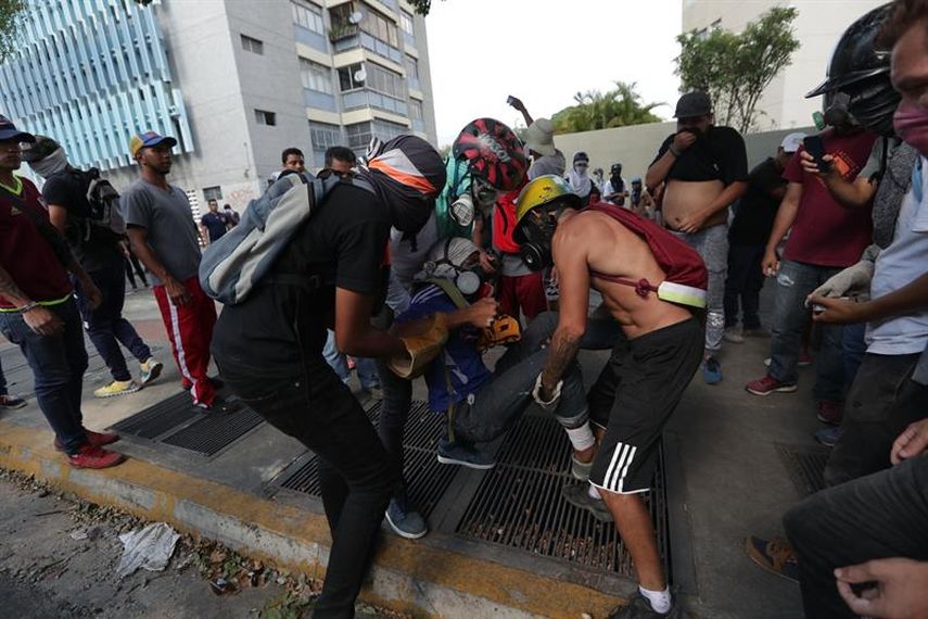 Manifestantes opositores ayudan a un hombre herido este miércoles en las calles de Caracas (Venezuela).