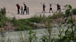 Migrantes venezolanos levantan los brazos en gesto de saludo después de cruzar el Río Bravo, o Río Grande para solicitar asilo político, visto desde Ciudad Juárez, Estado de Chihuahua, México, el 12 de septiembre de 2022.