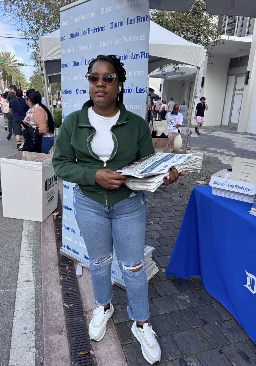 Ilen, promotora de DIARIO LAS AMÉRICAS distribuye ejemplares impresos entre el público.