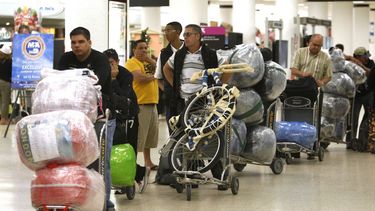 Varios viajeros esperan una fila con su equipaje en el aeropuerto internacional de Miami antes de viajar a Cuba. 