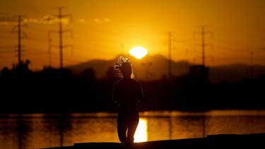 Una mujer corre cerca del Lago Tempe Town al amanecer, el 12 de julio de 2023 en Tempe, Arizona.&nbsp;