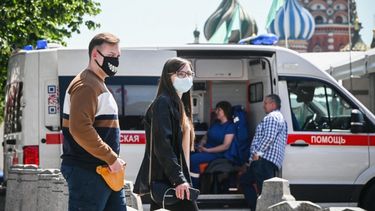 Personas con mascarillas caminan por la Plaza Roja frente a la catedral de San Basilio en el centro de Moscú pasando una ambulancia el 18 de junio de 2021, en medio de la crisis relacionada con la pandemia Covid-19 causada por el nuevo coronavirus.