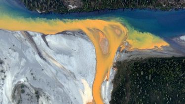 Una vista aérea del río Kutuk en el Parque Nacional Puertas del Ártico de Alaska que parece pintura naranja derramándose en el agua azul clara.&nbsp;