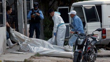 Personal forense retira los cuerpos de once personas muertas en un salón de billar en Choloma, a unos 180 km al norte de Tegucigalpa, el 25 de junio de 2023. &nbsp;