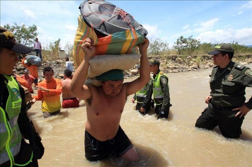 Cientos de colombianos cargan sus pertenencias por el río Táchira desde Venezuela hacia el sector La Parada, Colombia. (EFE)