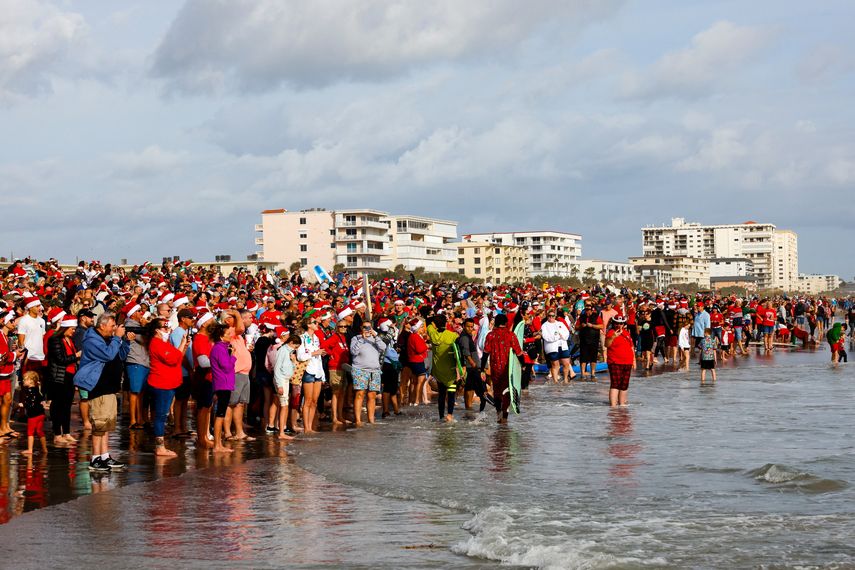 Los asistentes observan a los surfistas durante el 15º evento anual Surfing Santas en Cocoa Beach, Florida, el 24 de diciembre de 2023.