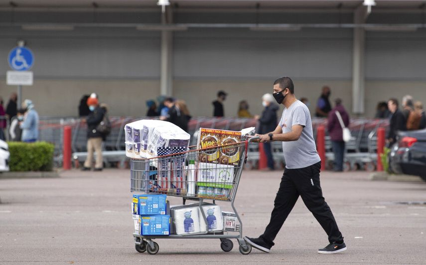Una persona sale con sus compras mientras otras hacen fila para entrar a un supermercado en Leicester, Inglaterra, el domingo 1 de noviembre de 2020