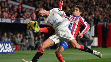 El defensor Kike Salas (izquierda), del Sevilla, batalla por el balón contra el atacante Giuliano Simeone, del Atlético de Madrid, en un partido, el 8 de diciembre de 2024.