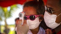 A una niña con mascarilla para protegerse del nuevo coronavirus le toman la temperatura en un puesto de control policial en la entrada de la provincia de La Habana, Cuba, el lunes 10 de agosto de 2020.&nbsp;