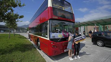 Pasajeros posan para una foro delante de un autobús antes de abordar, en Hong Kong, el sábado, 16 de octubre del 2021. Residentes insomnes pudieran encontrar alivio en un nuevo autobús en Hong Kong. El recorrido de 76 kilómetros (47 millas) y cinco horas en un bus de dos pisos alrededor del territorio busca atraer a personas que se quedan dormidas fácilmente en viajes largos. Fue inspirado por la tendencia de trabajadores cansados a dormirse en el transporte público.&nbsp;