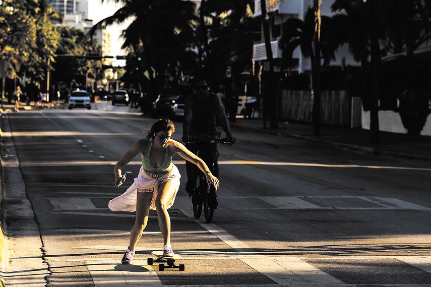 Una mujer rueda un patineta por las calles de Ocean Drive en, Miami Beach.